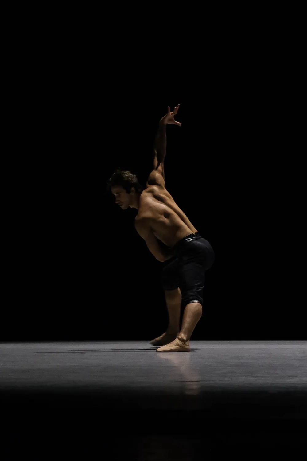 Philip performing on a dark stage, one arm raised